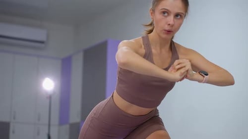 Focused Woman in Brown Performing Squat Exercise in Gym