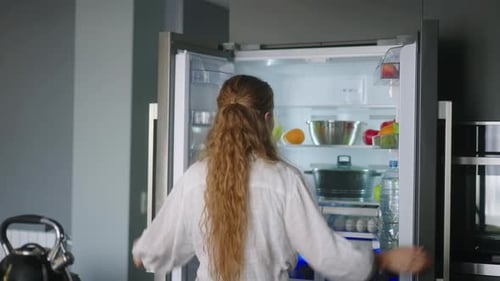 Woman Chooses Fresh Fruit From Refrigerator in Kitchen
