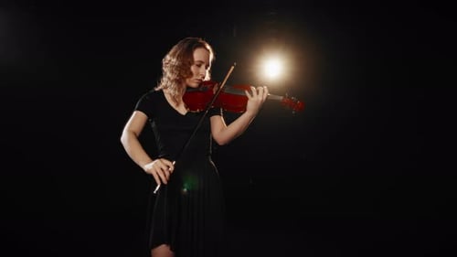Woman Playing Violin in Dark Setting