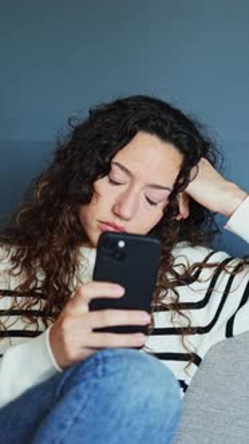 Woman getting bored scrolling and texting on smartphone