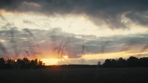 Golden Sunset Over Rural Field with Dramatic Clouds