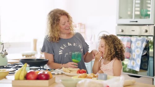 Smiling Woman and Child Eating Breakfast at Kitchen Table