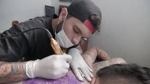 Tatto artist cleaning and checking up tattoo progress