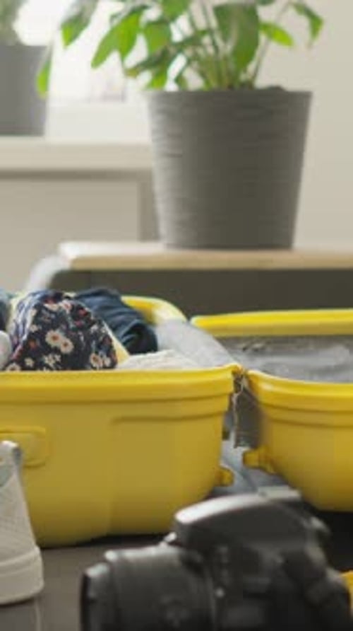 Woman Packing Yellow Suitcase at Home