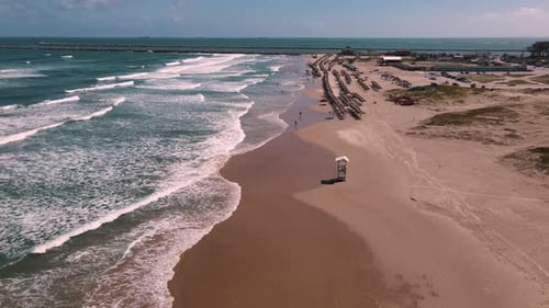 Picturesque Sandy Beach with People, Waves, and Umbrellas