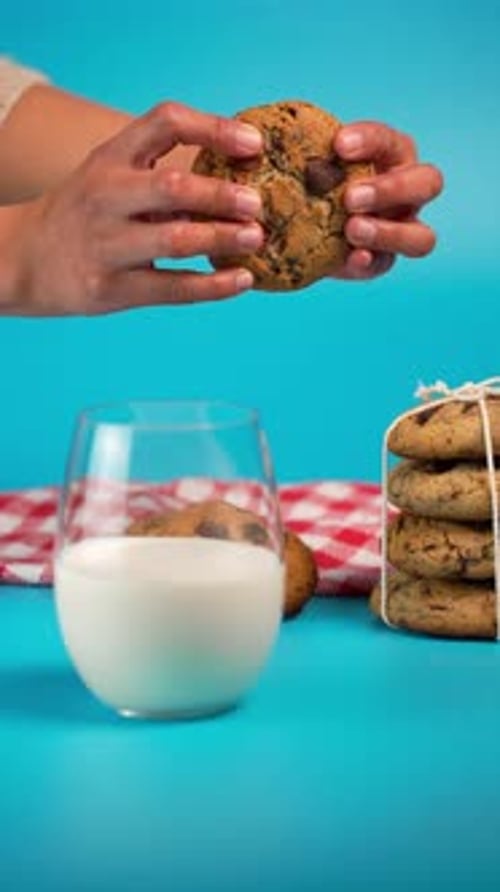 Vertical Video, The Hands Of A Latina Woman Breaking A Chocolate Chip Cookie In Half