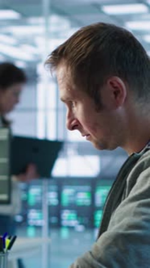 Portrait of Smiling Engineer Inspecting Server Rows in Data Center