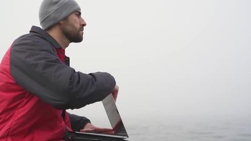 Digitaler Nomade öffnet Laptop auf See mit Nebel am Wintermorgen