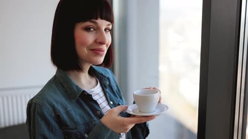 Woman with Coffee Cup Enjoying View From Panoramic Window