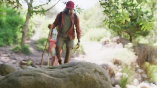 Happy diverse couple hiking with backpacks in park, slow motion