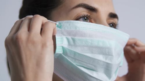 Woman Adjusting a Light Blue Surgical Mask