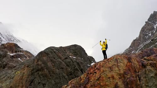Hiker Celebrating Reaching the Summit in the Snowy Mountains