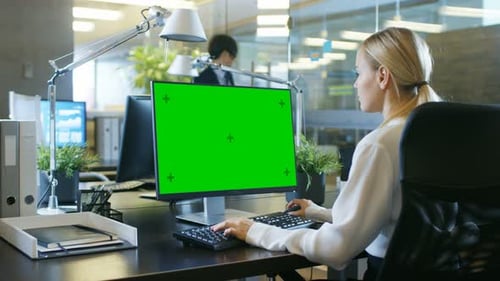 In the Office Businesswoman works at Her Desk on a Personal Computer with Mock-up Green Screen. Col