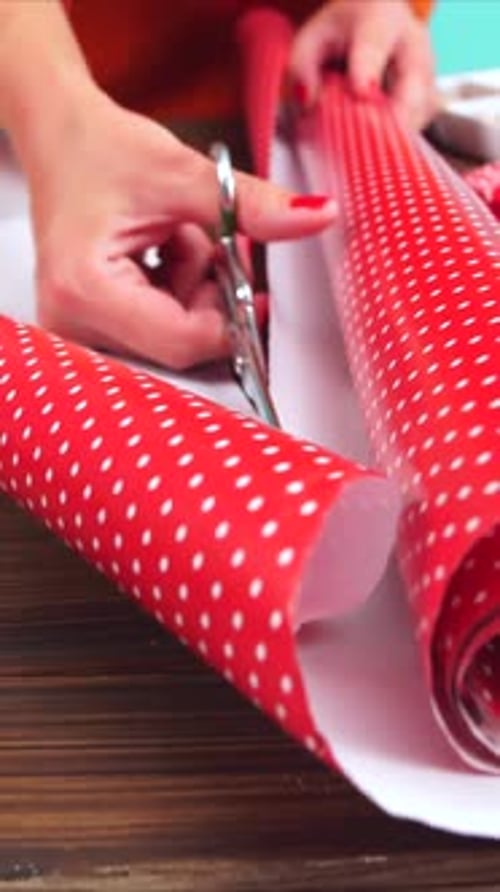 Woman Cutting Red Polka Dot Wrapping Paper with Scissors