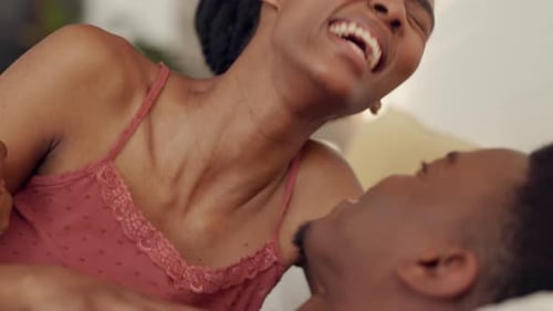 Woman Laughing on Top of Man in Bed