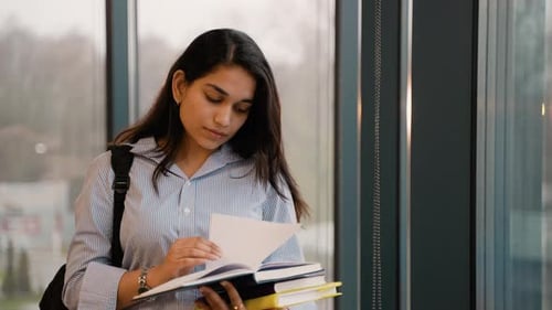 Young Indian Student Woman Reading Books in University Campus Hall