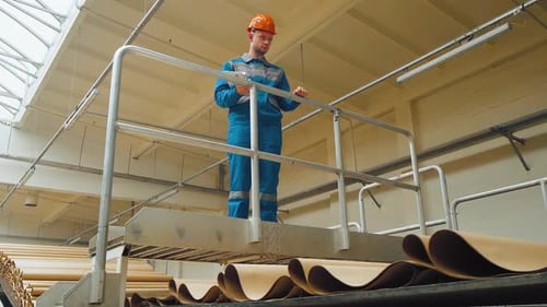 An Engineer Worker at a Packaging Factory Controls a Corrugated Cardboard Conveyor Focused