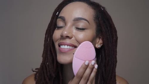 Woman Cleansing Face with Electronic Skin Device