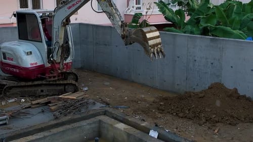 Excavator Moving Dirt Near Foundation