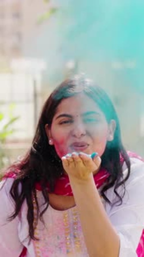 Smiling Woman Blowing Colorful Powder for Holi Festival