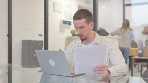 Frustrated Man Working on Laptop in Office