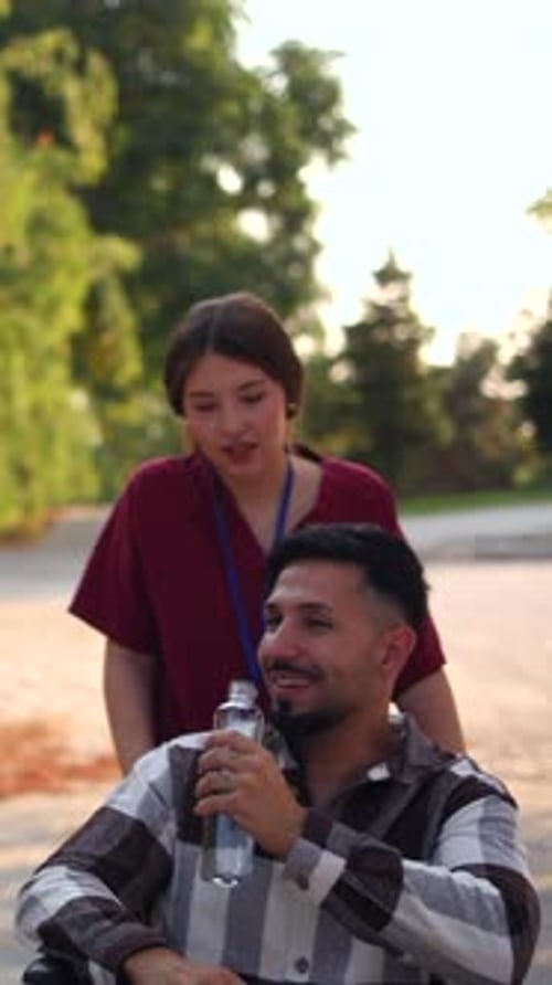 Woman Pushing Man in Wheelchair Through Green Park