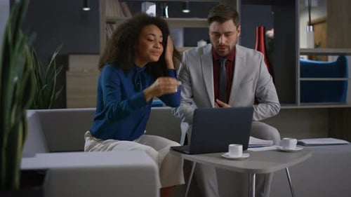 Two Colleagues Work Together on Laptop in Office