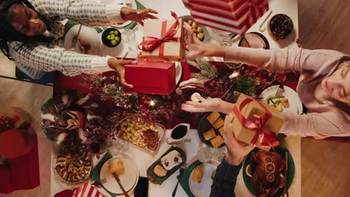 Friends Giving Presents to Each Other Top View Celebrating New Year Sitting at Dining Table