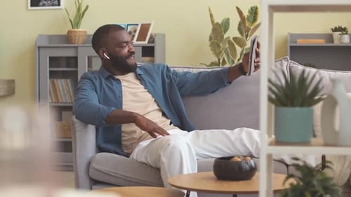 Man Relaxes at Home Talking on Tablet