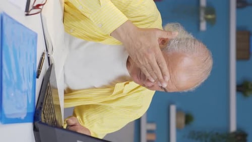 Vertical video of Home office worker old man has eye pain.