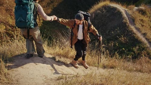 Man Passes Steep Slope and Helps African American Wife with Hand