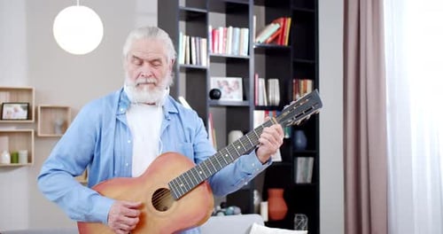 Senior Man Playing Acoustic Guitar at Home