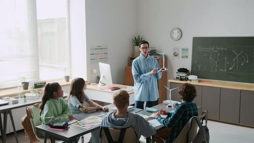 Teacher, Holding Model Wind Turbine, Addressing Attentive Students in Classroom