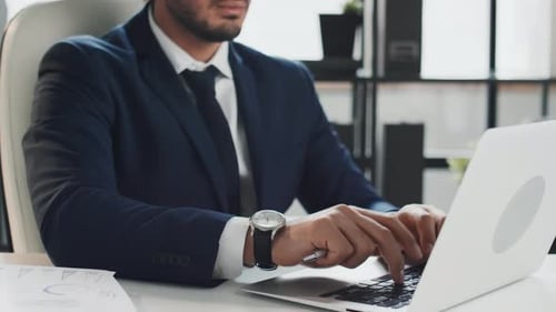 Young Adult Typing on a Laptop in Office