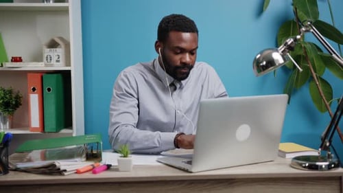 A Dedicated Professional Man Engaged in Complex Work While Utilizing His Laptop at a Modern Desk