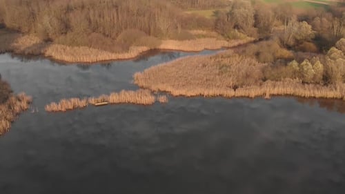 Aerial view of a natural swamp during golden hours with cloud reflection on the water. Wild vegetati