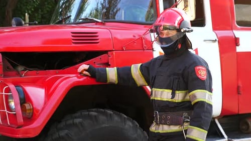 Firefighter Standing Near a Bright Red Fire Engine