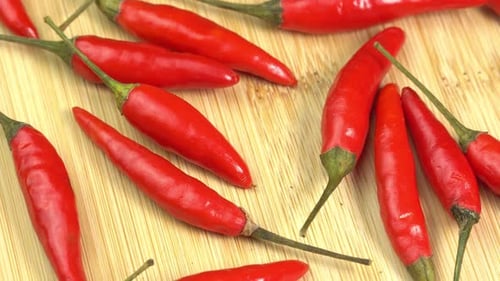 Red Chilli Peppers Rotating on a Wooden Cutting Board. Hot Spicy Food concept