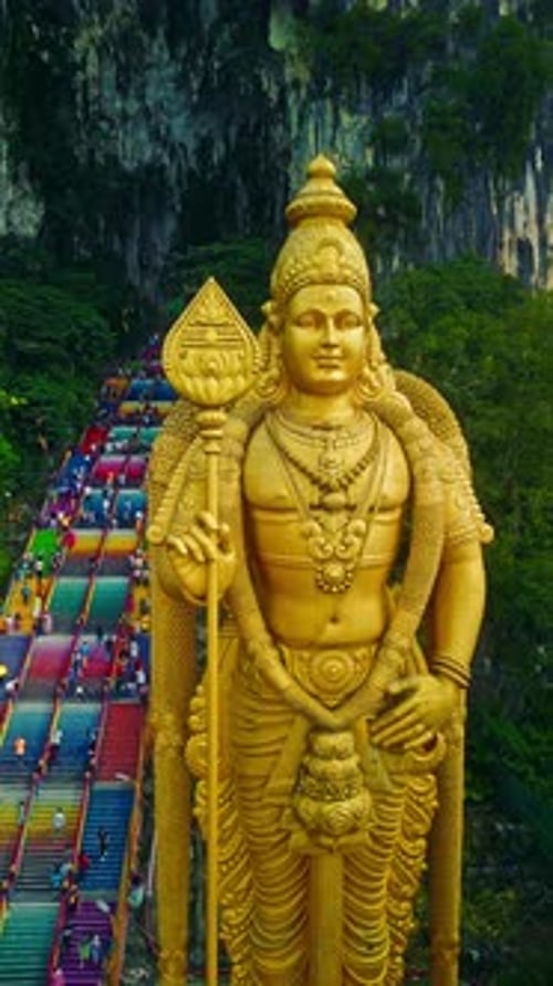 Statue de Lord Murugan dans les grottes de Batu avec des marches vibrantes pendant la journée, prise de vue verticale en Malaisie