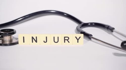 Stethoscope and Word Injury on White Background