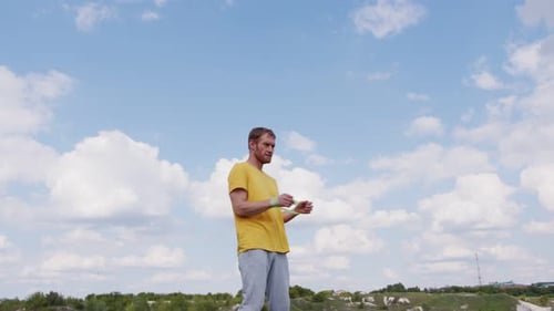 Um esportista profissional com uma camisa amarela está segurando um expansor de elástico. Ele parece focado e
