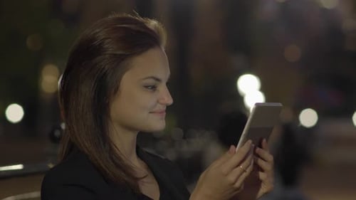 Young Woman Using Tablet Computer In The Park At Night