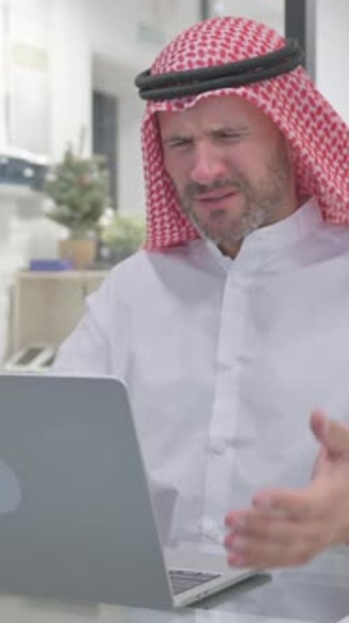 Frustrated Man in Keffiyeh Using Laptop at Work