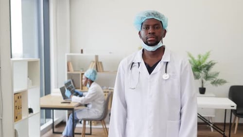 Confident Male Doctor Wearing Protective Gear Standing Arms Crossed in Hospital