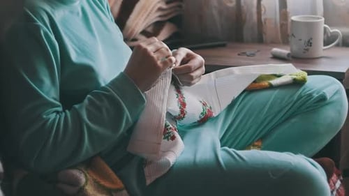 Woman Embroidering Fabric in Cozy Indoor Setting