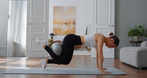 Woman Performing Mountain Climber Exercise on Yoga Mat in Modern Home Interior with Natural Light
