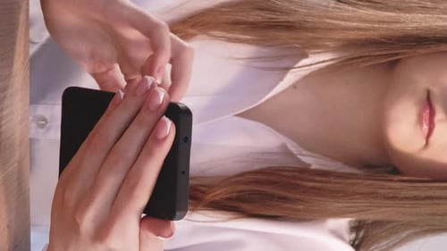 Woman Uses Phone at Desk, Vertical Format