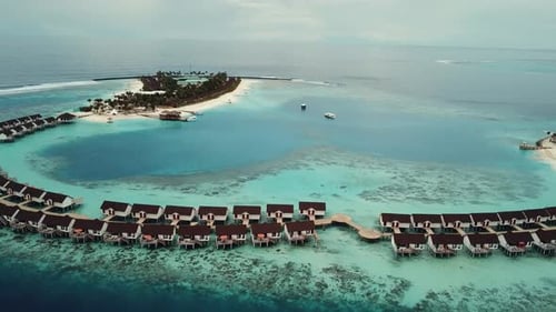 Vídeo de drone de um resort tropical nas Maldivas, lagoa azul, palmeiras verdes, clima ensolarado, turquesa