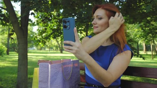 Woman Adjusts Hair While Taking Selfie in Park
