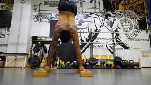 Muscular Man Performing Handstand in Gym